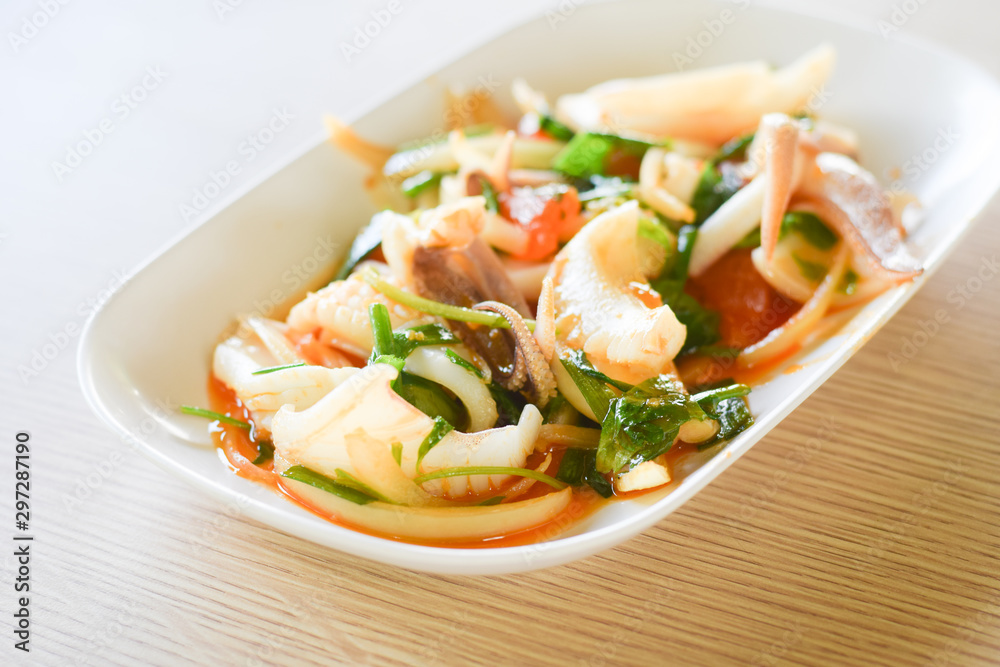 Stir fried squid with salted egg yolk on white dish on table background. thai food.