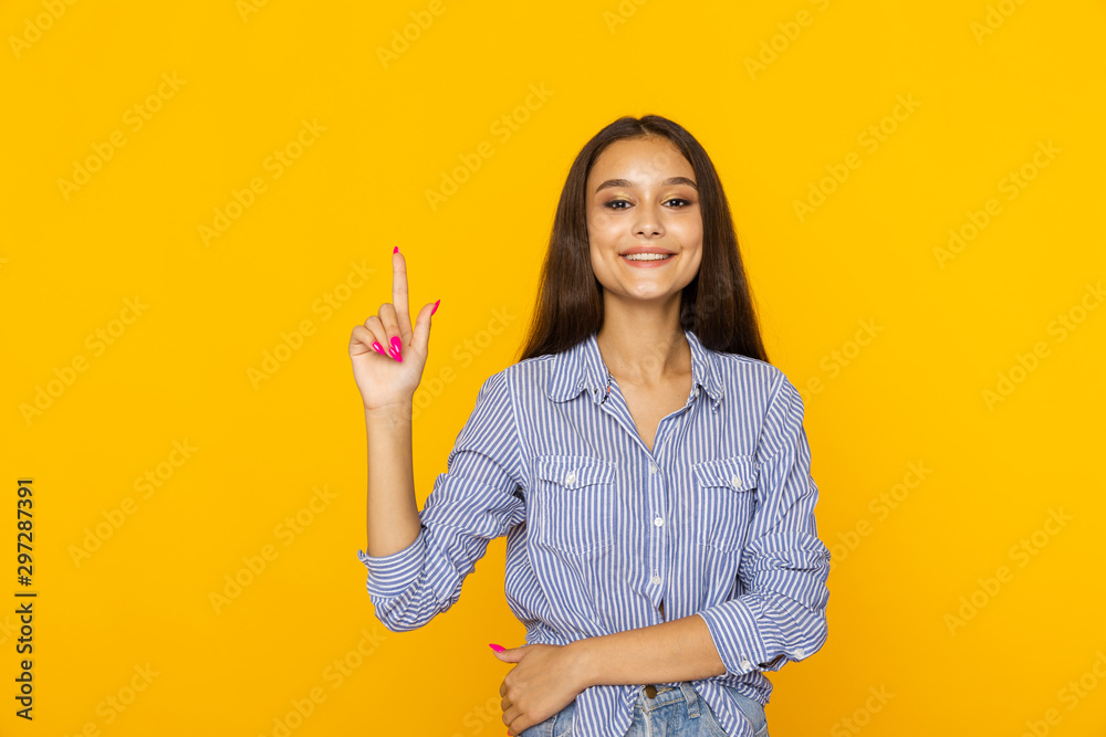 Happy female model is on the yellow studio pointing something by finger isolated Happy female model is on the yellow studio pointing something by finger isolated