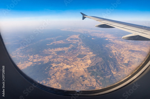 Looking through aircraft window during flight. Aircraft wing over blue skies and pyrenees mountains.Copy space.
