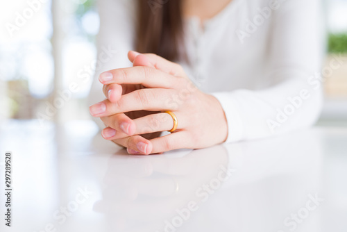 Close up of woman hands wearing wedding alliance ring over white table