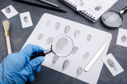 Concept of criminal investigation. Investigator wearing blue gloves and searching fingerprint as a evidence photo