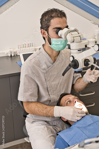 Dental doctor with microscope and hygienic gloves checking the dental health of his patient in a modern clinic