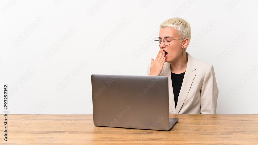 Teenager girl with short hair with a laptop yawning and covering wide open mouth with hand Teenager girl with short hair with a laptop yawning and covering wide open mouth with hand