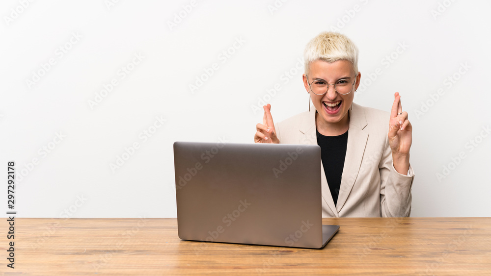 Teenager girl with short hair with a laptop with fingers crossing Teenager girl with short hair with a laptop with fingers crossing