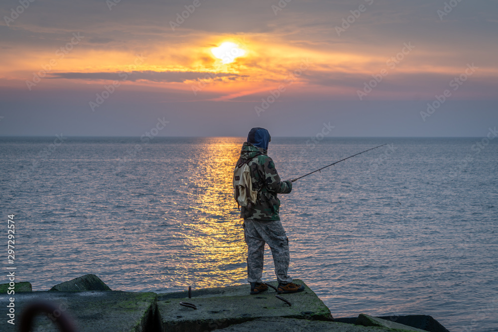 Man fishing from the pier during beautiful sunset 