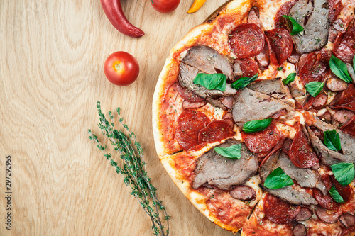 Italian, homemade pizza with meat, salami and hot pepper on a wooden table. Top view food with copy space. Flat lay