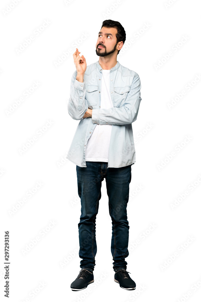 Full-length shot of Handsome man with beard with fingers crossing and wishing the best over isolated white background