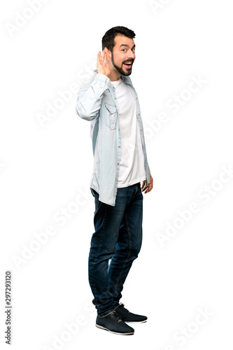 Full-length shot of Handsome man with beard listening to something by putting hand on the ear over isolated white background © luismolinero