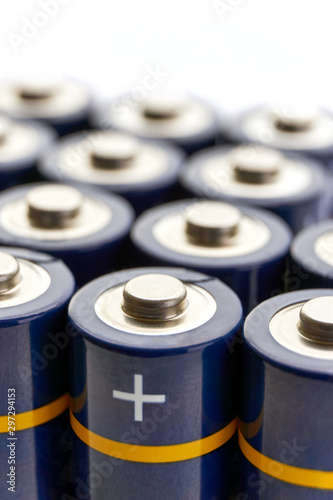 Batteries in rows. Close-up or macro of blue alkaline AA batteries with yellow stripes and plus sign on the positive pole. Vertical image with selective focus and isolated on top for copy space.
