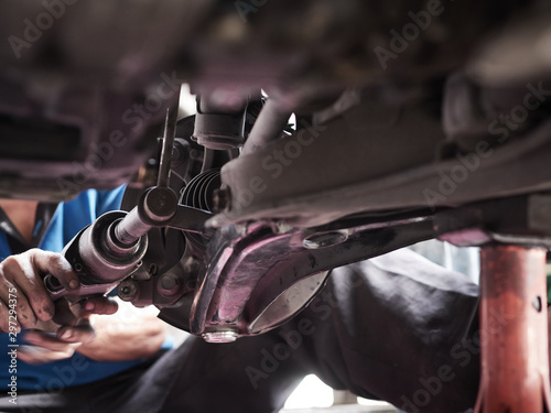 Car mechanic hands fixing tie rod Under the Vehicle. Mechanic technician working in the Professional Service.
