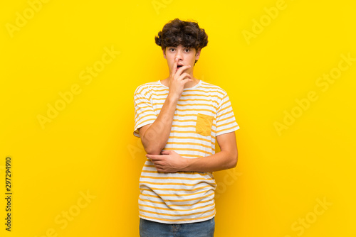 Young man over isolated yellow wall surprised and shocked while looking right