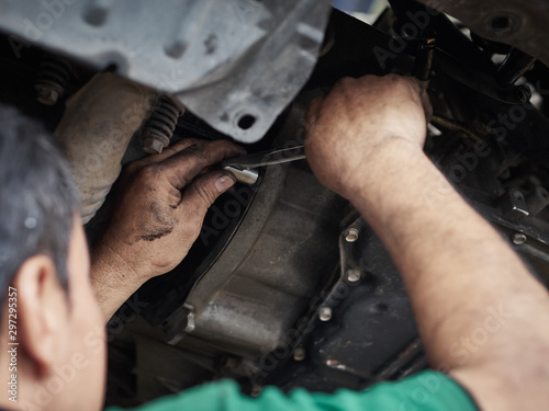 Automotive mechanic tightening the torque gear of the car. Mending, repair car in garage.