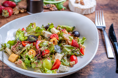 Gourmet green salad with cheese, grape, strawberries and cherry