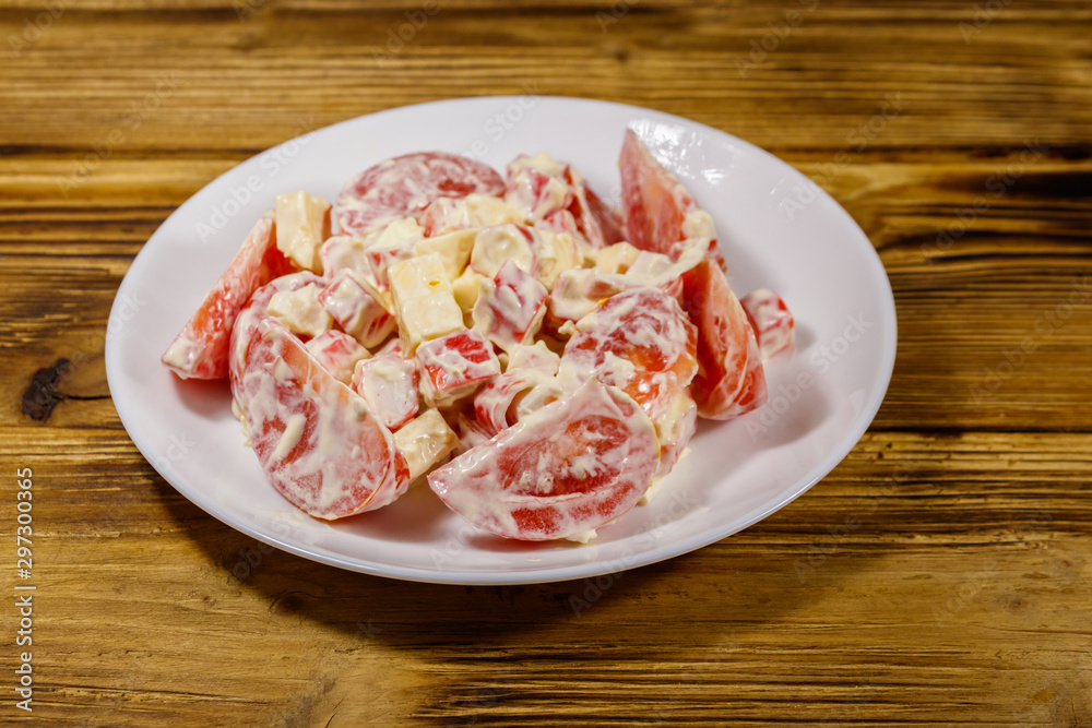 Tasty salad with crab sticks, cheese, tomato and mayonnaise on wooden table Tasty salad with crab sticks, cheese, tomato and mayonnaise on wooden table
