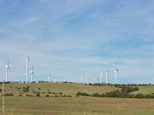 An array of large wind turbines moving to create kinetic energy for renewable energy supply on a sunny day located southeast of Lake George and north of Bungendore in New South Wales, Australia  photo