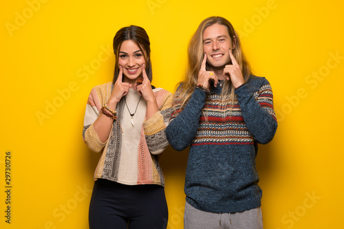 Hippie couple over yellow background smiling with a happy and pleasant expression