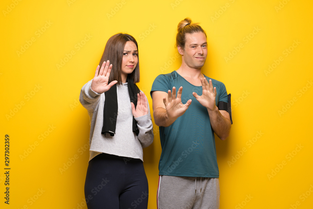 Group of athletes over yellow background is a little bit nervous and scared stretching hands to the front Group of athletes over yellow background is a little bit nervous and scared stretching hands to the front