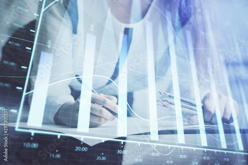 Double exposure of hands making notes with forex chart huds. Stock market concept.