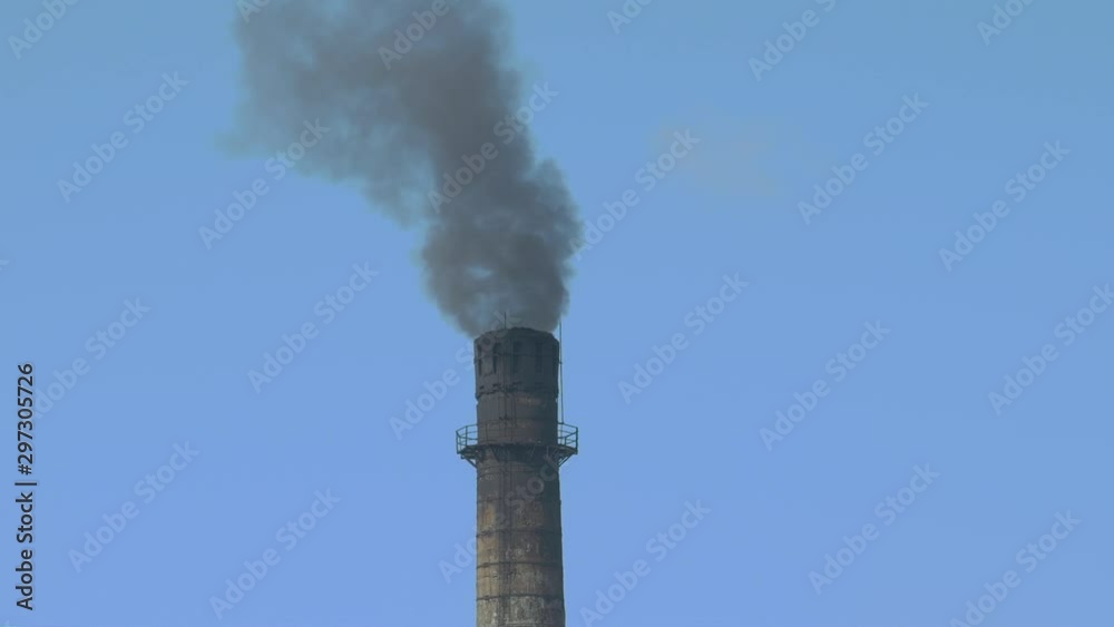Black smoke from a factory chimney against a blue sky