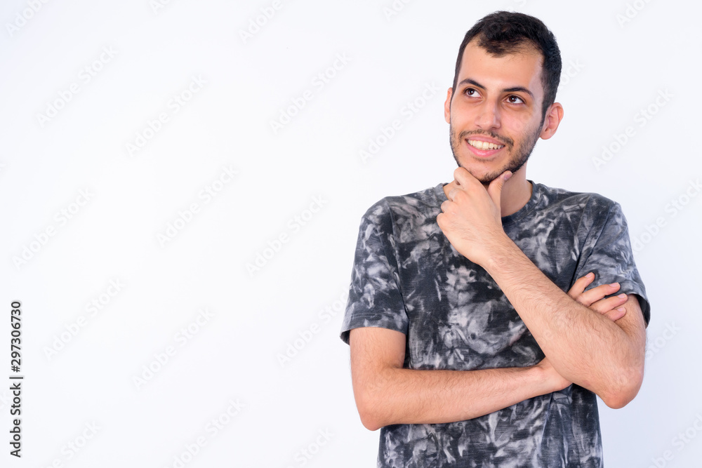 Portrait of happy young bearded Persian man thinking and looking up Portrait of happy young bearded Persian man thinking and looking up