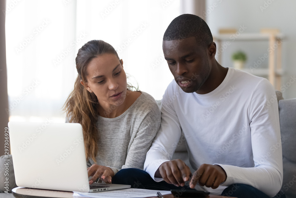 Multiethnic couple manage finances paying taxes online Multiethnic couple manage finances paying taxes online