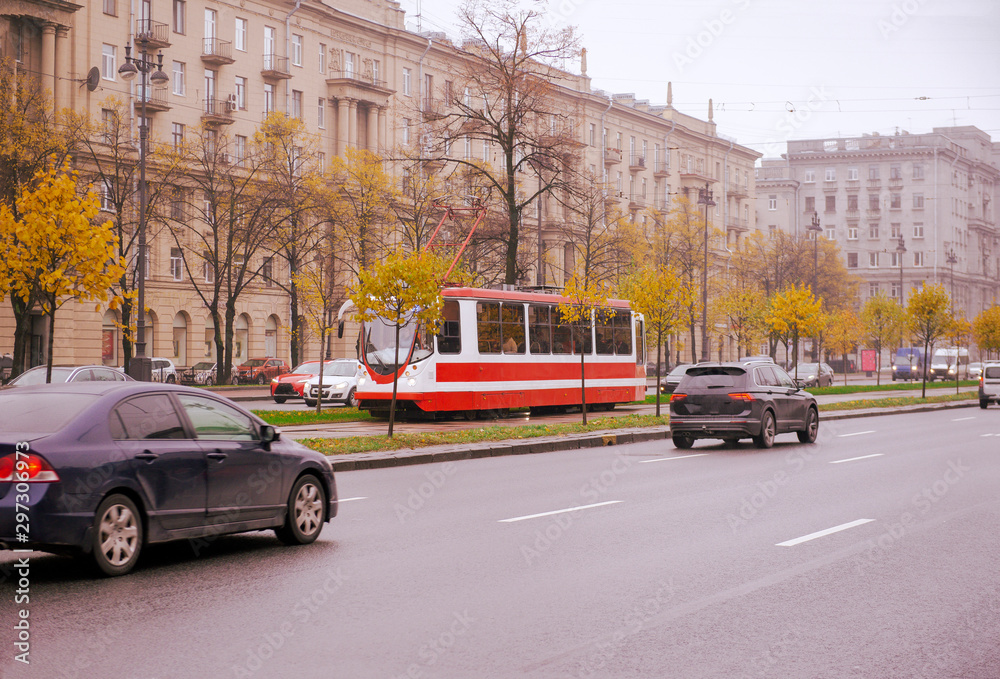 cars, tram on the road in St. Petersburg on an autumn cloudy day, traffic, buildings in the city center, trees with yellow leaves, October 2019,