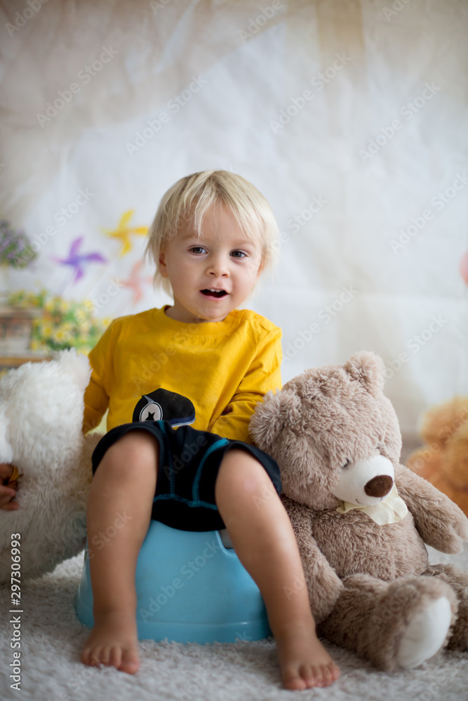 Cute toddler boy, potty training, playing with his teddy bear Cute toddler boy, potty training, playing with his teddy bear