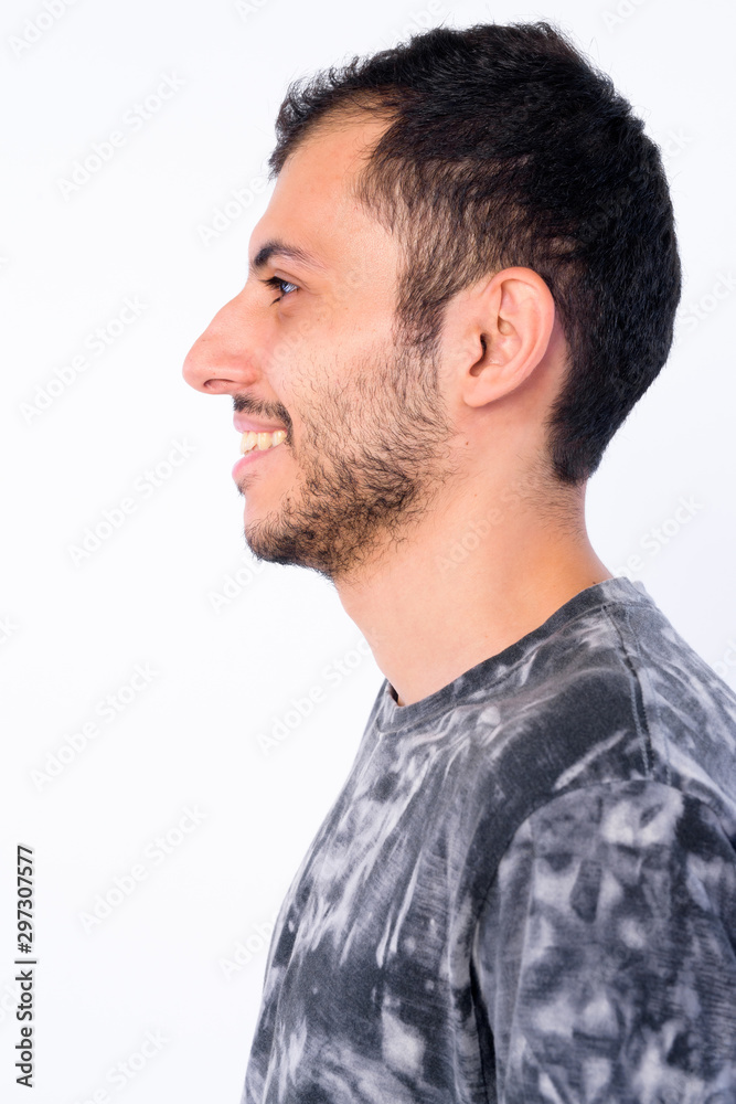 Fototapeta premium Closeup profile view of happy young bearded Persian man smiling