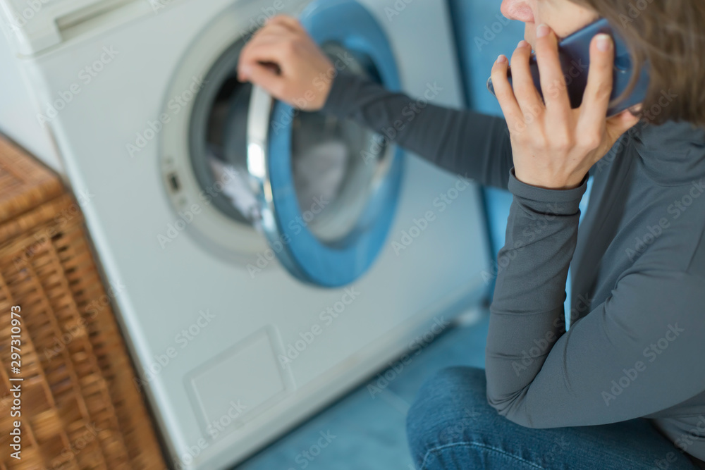 Fototapeta premium A woman calls a repair service for a breakdown of a washing machine. 