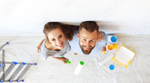 фотографія young happy couple is repairing and painting   wall at home