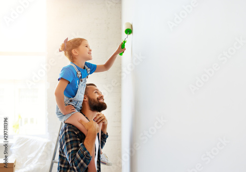 Repair in apartment. Happy family father and child daughter paints wall