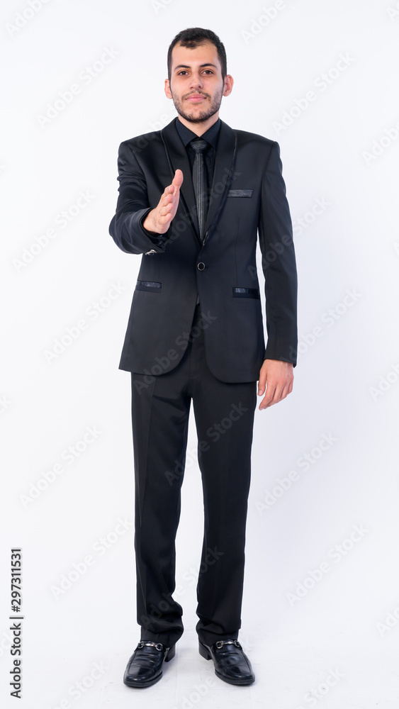 Full body shot of young bearded Persian businessman in suit giving handshake Full body shot of young bearded Persian businessman in suit giving handshake