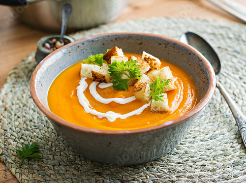 Pumpkin soup in a bowl served with parsley and croutons. Vegan soup. Thanksgiving day food. Halloween meal.