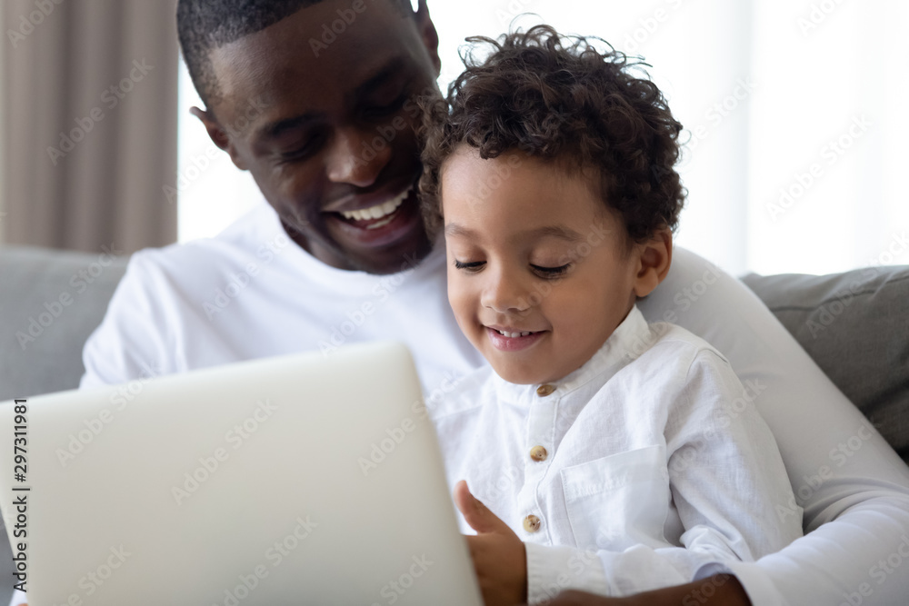Loving dad relax using laptop with little biracial son Loving dad relax using laptop with little biracial son