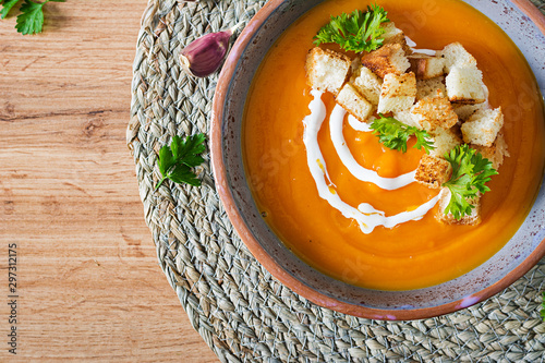 Pumpkin soup in a bowl served with parsley and croutons. Vegan soup. Thanksgiving day food. Halloween meal. Top view