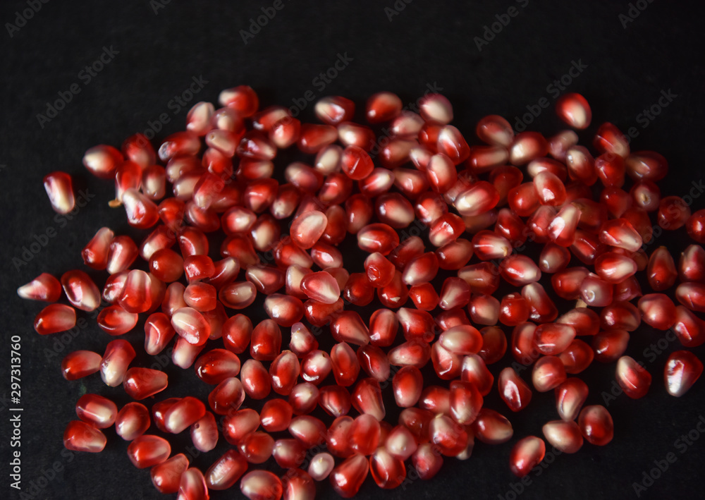 red pomegranate seeds on black background red pomegranate seeds on black background