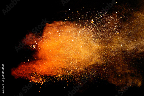Abstract orange powder explosion isolated on black background.