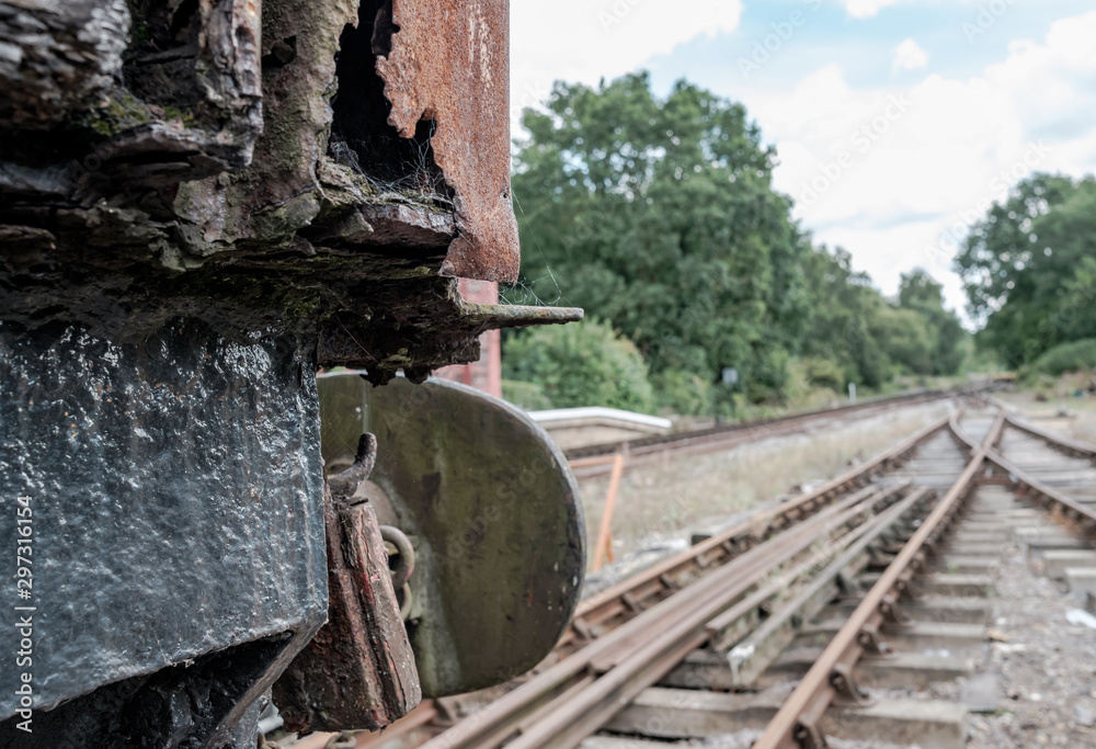 Shallow focus view of an abandoned British goods train in an advanced state of decay, with a view down a railway track located on a siding in the UK.