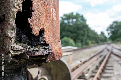 Fototapeta Naklejka Na Ścianę i Meble -  Shallow focus view of an abandoned British goods train in an advanced state of decay, with a view down a railway track located on a siding in the UK.