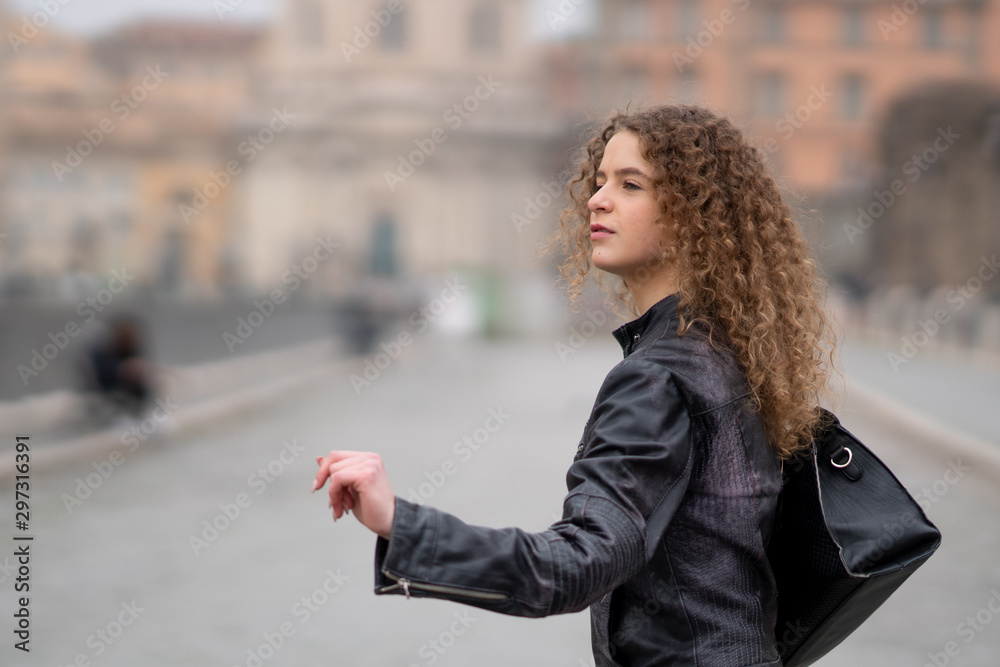 Attractive woman with curly hair and black leather jacket searching for a taxi in Rome, Italy Attractive woman with curly hair and black leather jacket searching for a taxi in Rome, Italy