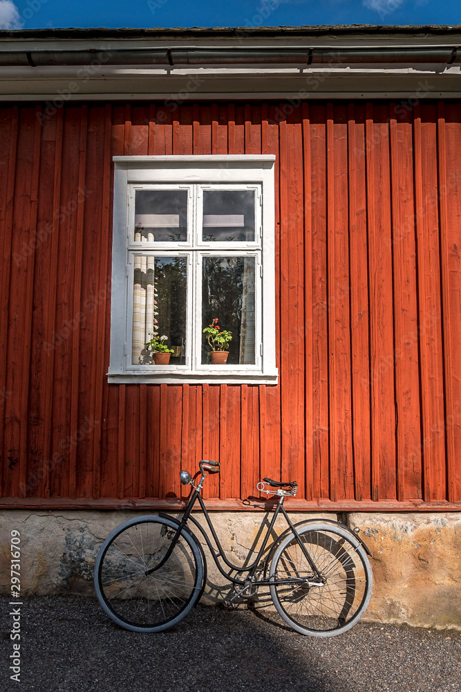 Vintage bicycle in front of old red wooden house