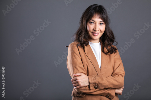 Portrait of successful business asian women with arms crossed and smile isolated over gray background.