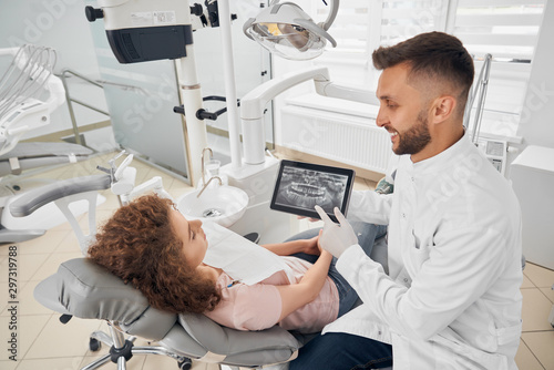Dentist keeping tablet and showing x ray picture of teeth