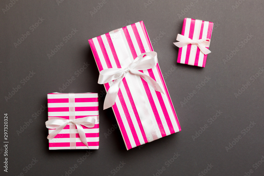 Fototapeta premium wrapped Christmas or other holiday handmade present in paper with White ribbon on black background. Present box, decoration of gift on colored table, top view