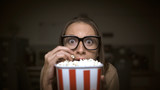 Woman watching a horror movie and eating popcorn