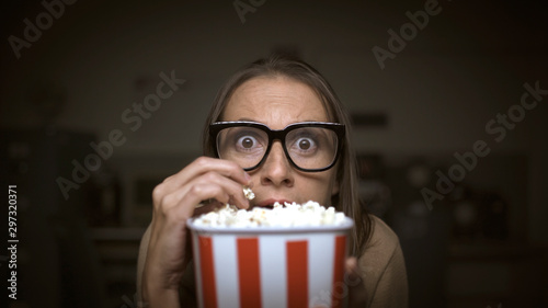 Woman watching a horror movie and eating popcorn photo