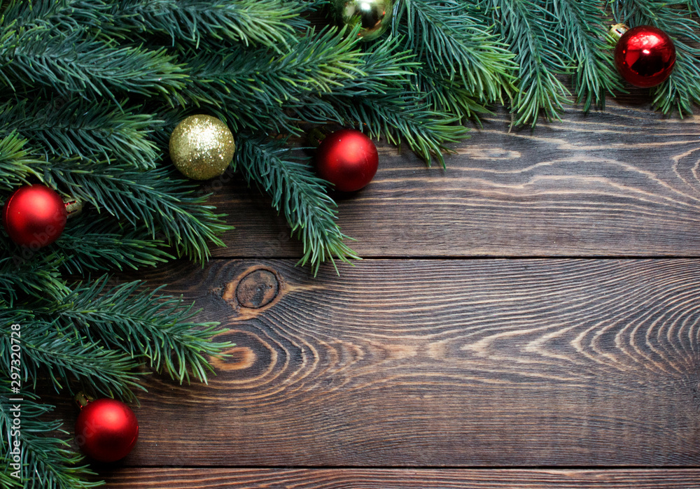 Frame of fir branches, red and gold Christmas tree balls on wooden brown background. 