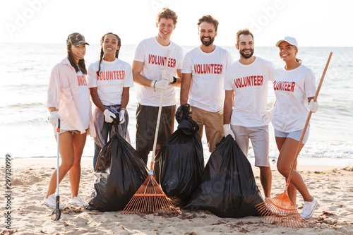 Photo of happy eco volunteers people cleaning beach from plastic trash