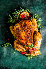 Traditional Christmas and Thanksgiving roasted whole chicken with fruit and rosemary. Dark green concrete table top view copy space