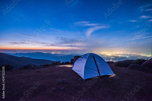 Tourist hikers tent in mountains at night with stars in the sky 